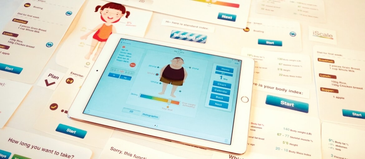 Tablet displaying a body index app with an overweight cartoon figure, surrounded by printed diet and exercise plans.