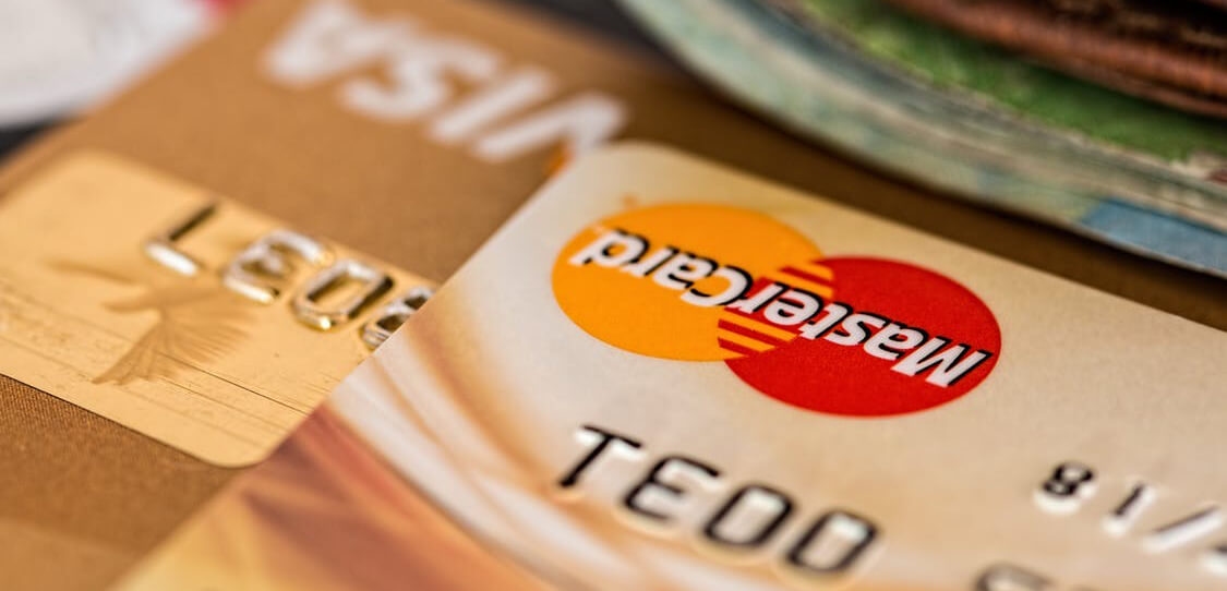 Close-up of two overlapping credit cards, one Mastercard and one gold card, on a table.