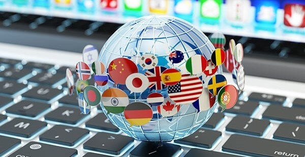 Transparent globe with various country flags on a laptop keyboard, symbolizing global connectivity.