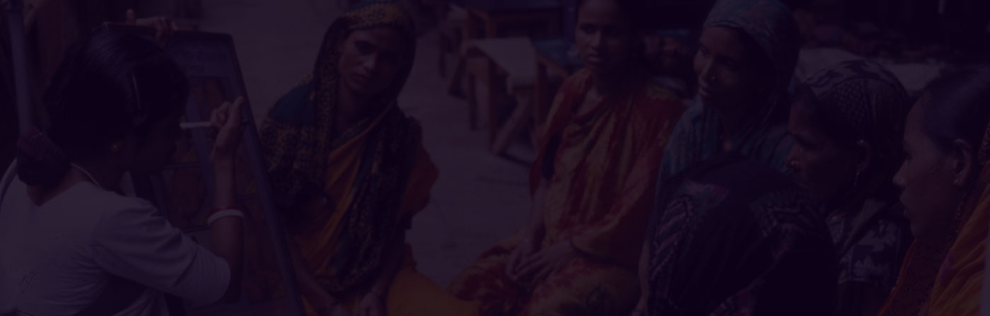 A group of women seated outdoors, engaged in a discussion or learning activity.