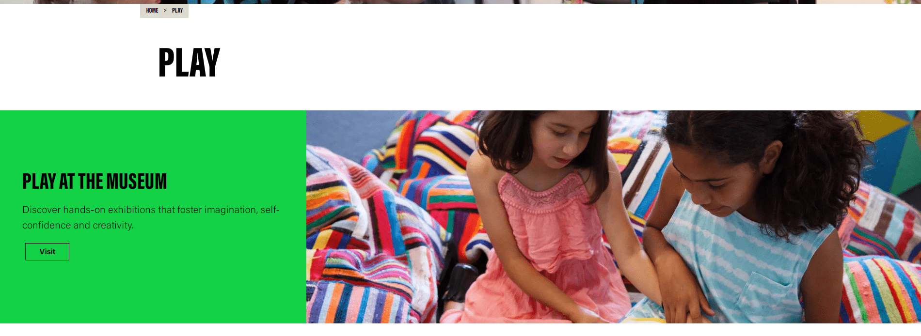 Two girls engaged in a hands-on museum activity on colorful striped cushions.