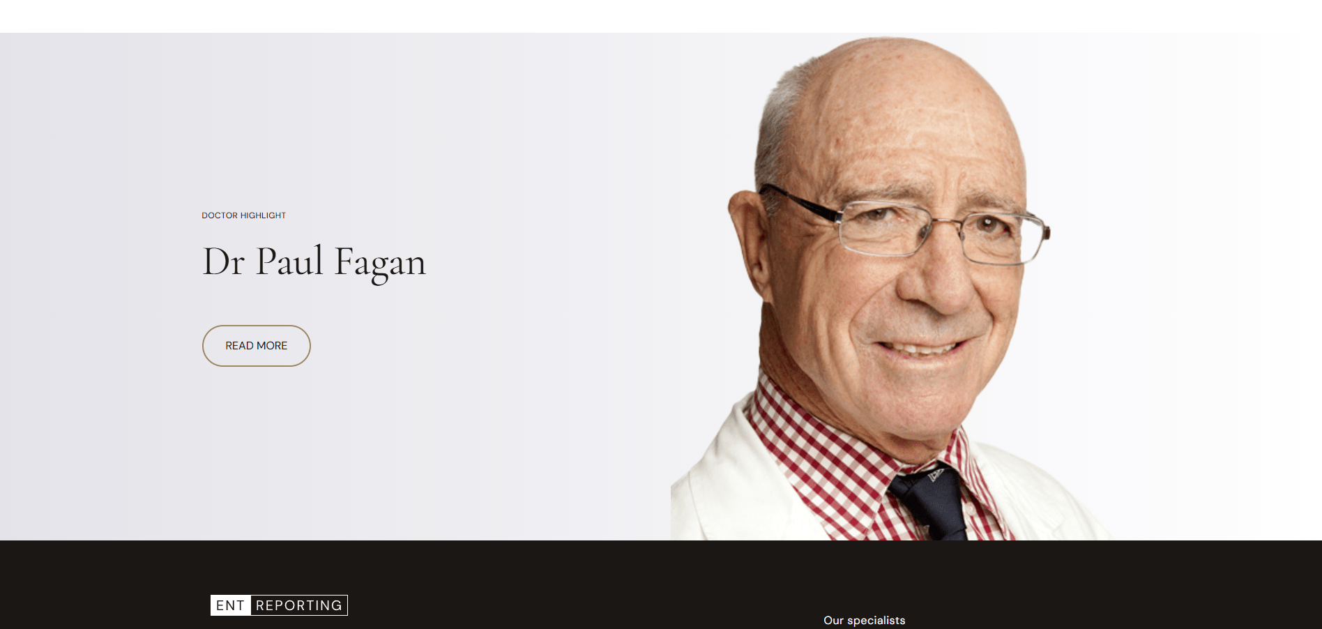 Smiling elderly doctor wearing glasses, white coat, checkered shirt, and dark tie on a light background.