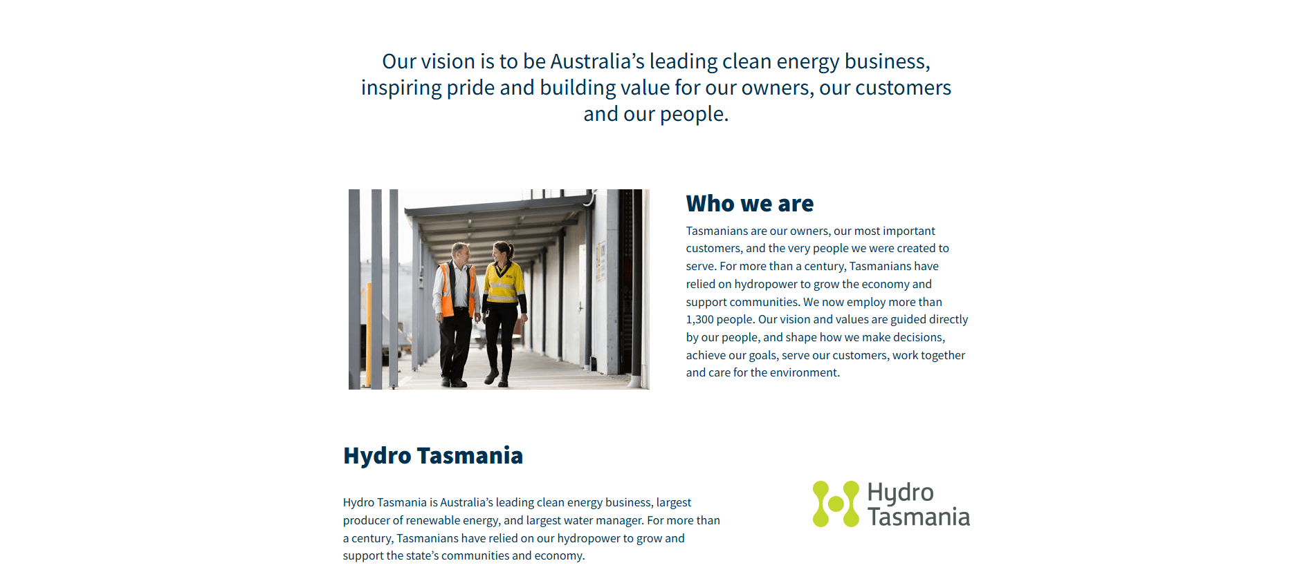 Two workers in safety gear walking and talking in an industrial corridor at Hydro Tasmania.