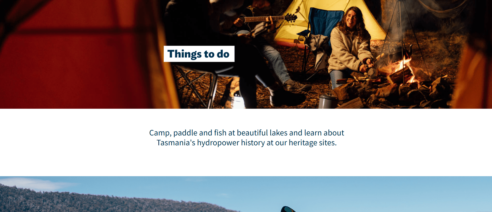 People camping and sitting around a campfire at night near a tent outdoors.